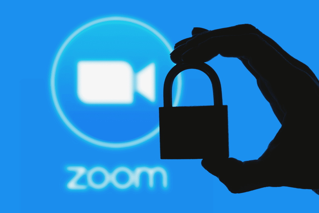 A silhouette of a padlock is held before a blue screen with the Zoom logo