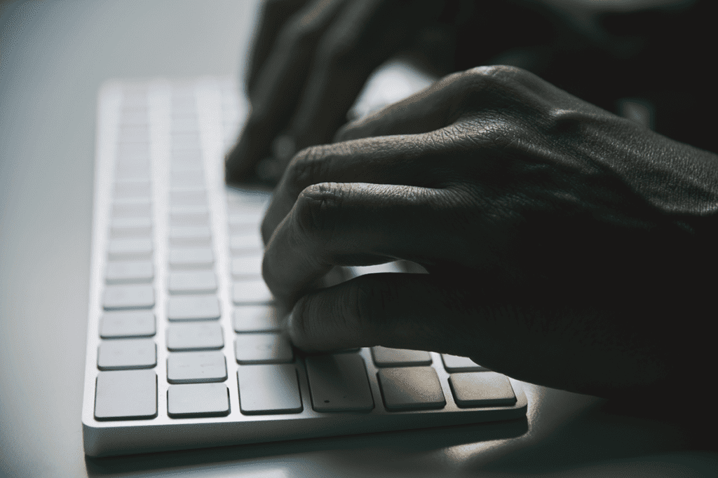 A dark image of a shadowy person typing on a keyboard, assuming to be doxing a victim