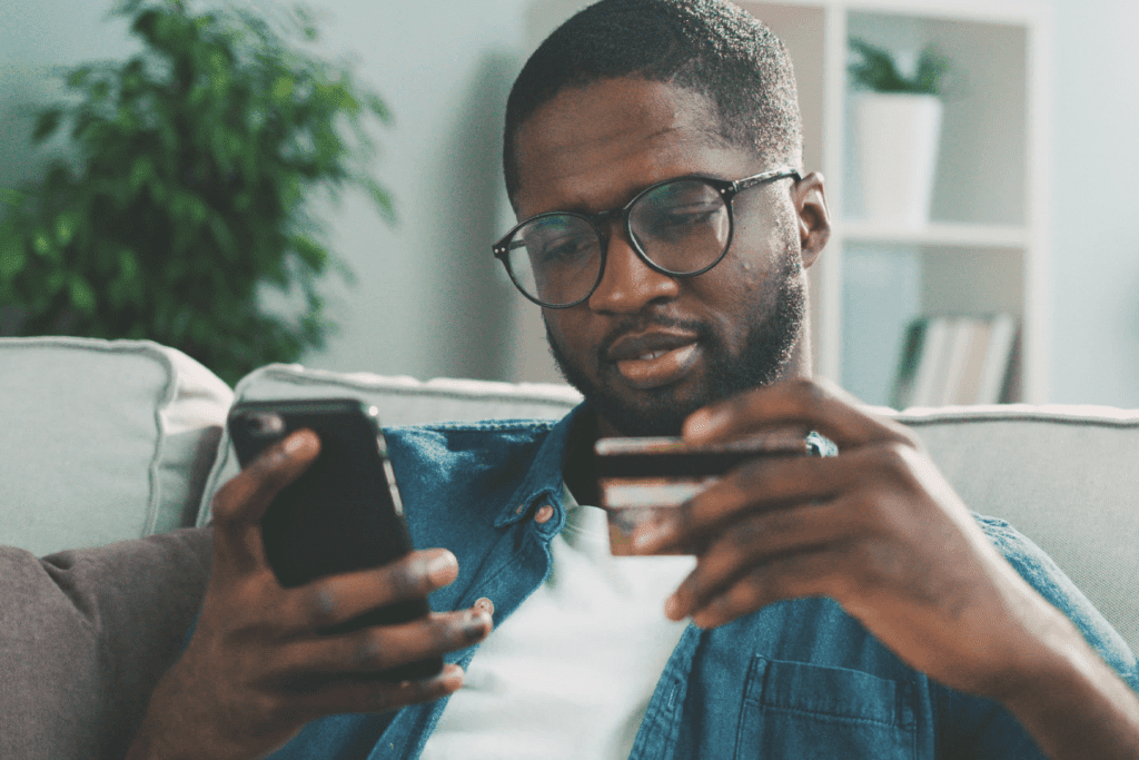 A man holding a credit card and mobile, using vpn for online shopping to keep the connection secure during purchase.