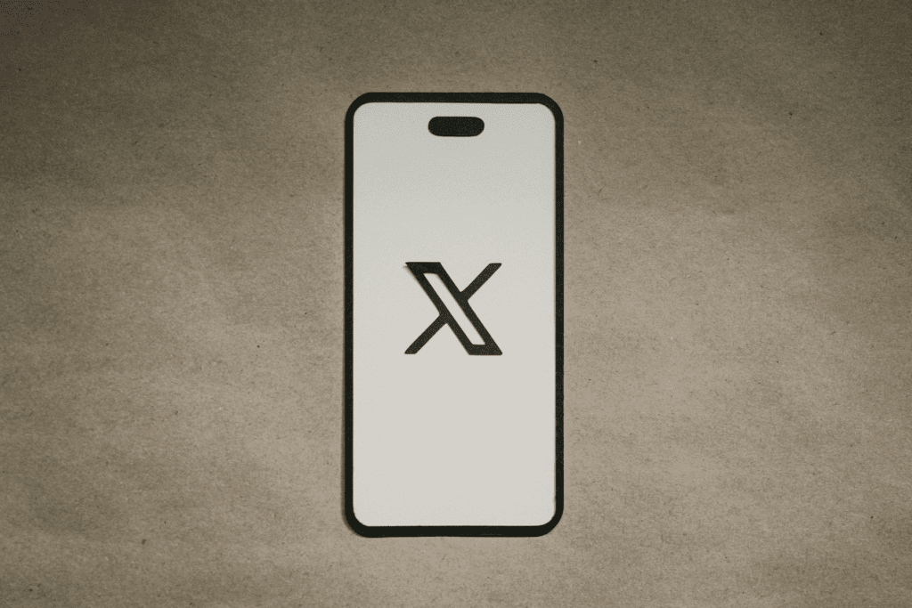 A phone has the X logo displayed on the screen decorative images for how to delete twitter account data and profile