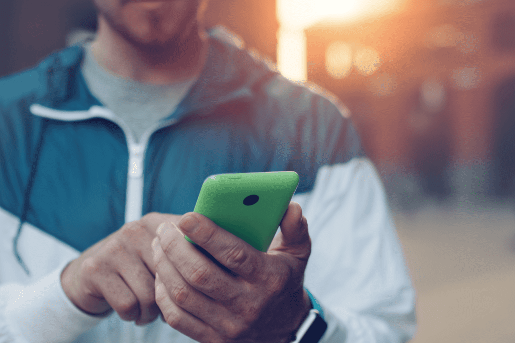 A person is seen holding a green smartphone visualizing how to block a number on android