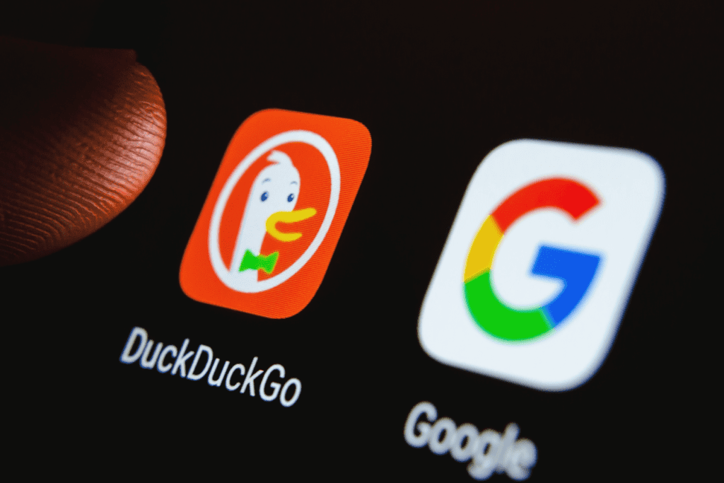 The DuckDuckGo app icon appears on a phone screen comparing the private search engine with a popular competitor