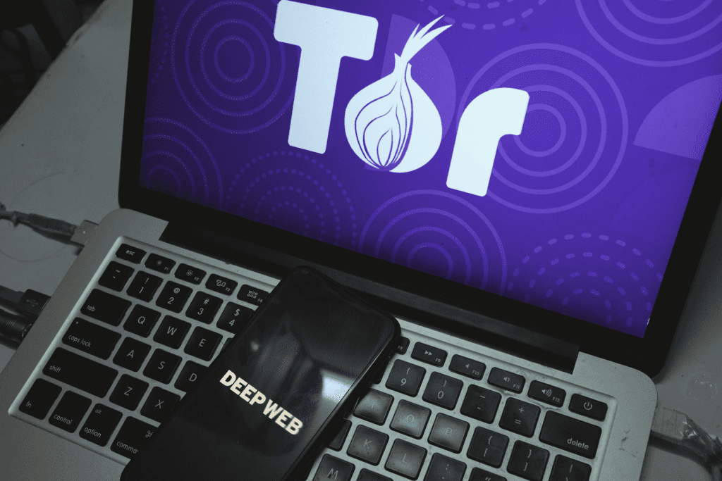 A laptop computer displays the Tor logo, the browser used to access the dark web and onion sites.