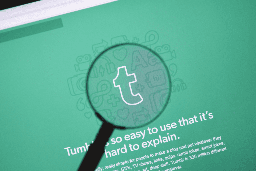 A magnifying glass focuses on the logo for Tumblr on its site homepage to visualize how to delete tumblr account and data