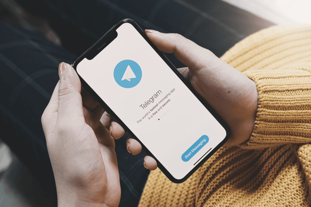A woman holds her phone on welcome screen after learning how to delete the Telegram app