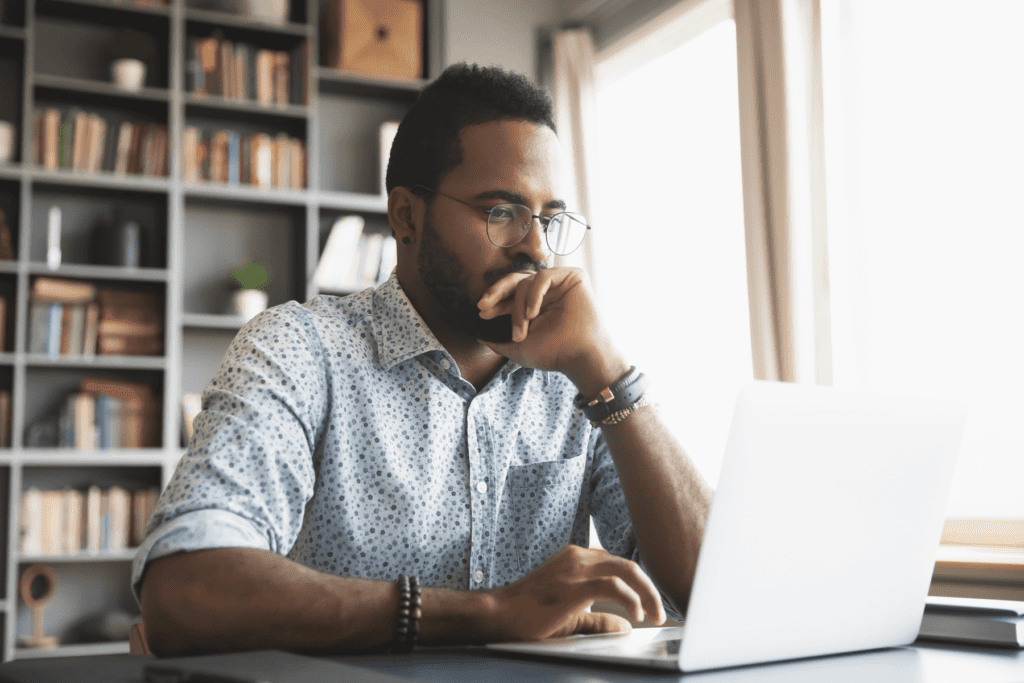 A man using a laptop appears with a contemplative expression while deciding to use TCP vs UDP