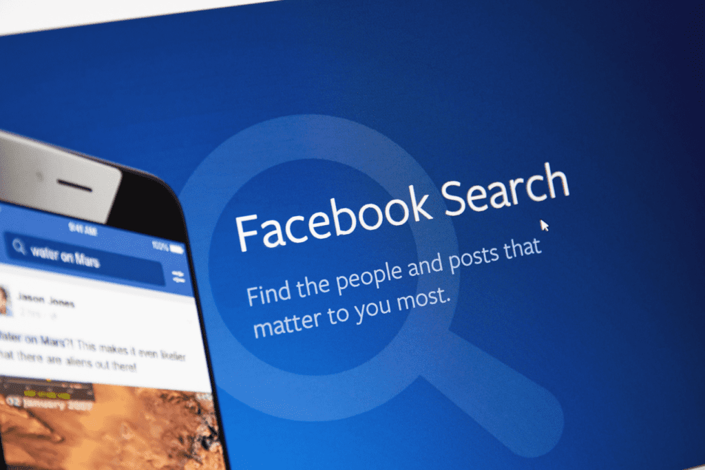 A phone displays the Facebook app in front of a monitor for Facebook Search. Visualizing how to delete Facebook search history