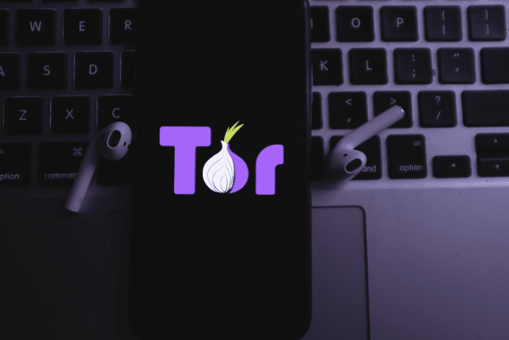 A phone loading the Tor Browser rests on a keyboard, visualizing a Tor VPN setup