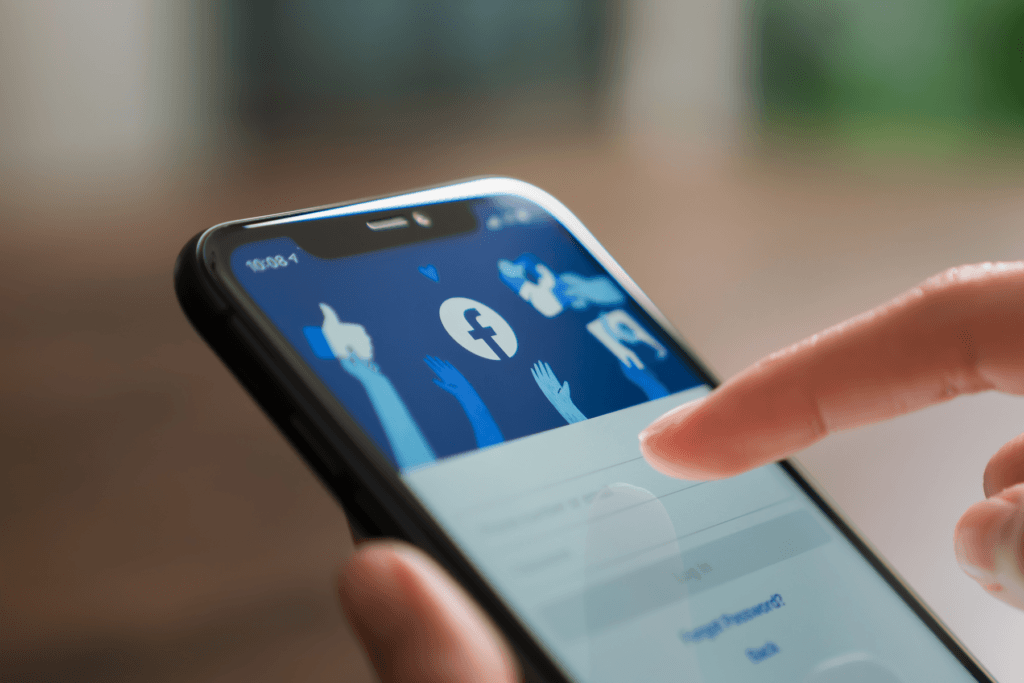 A person uses their phone which displays the Facebook login screen
