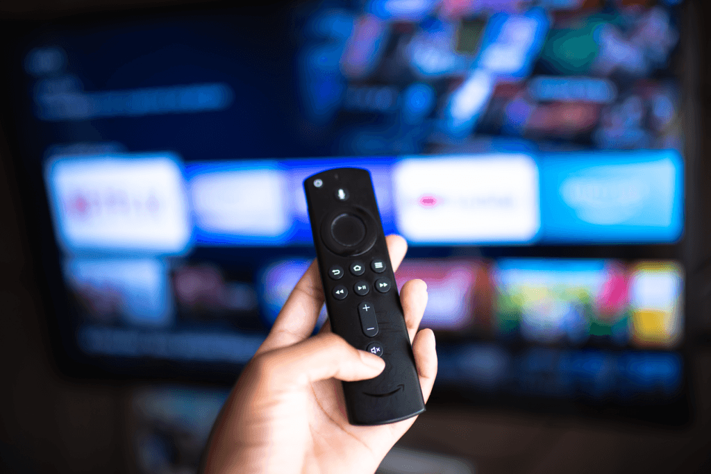 Image of a person holding their Fire Stick remote while looking at the Fire Stick apps screen deciding which to open