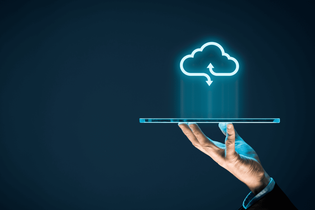 A person holds a smartphone that projects a cloud storage icon with arrows to symbolize uploads and downloads