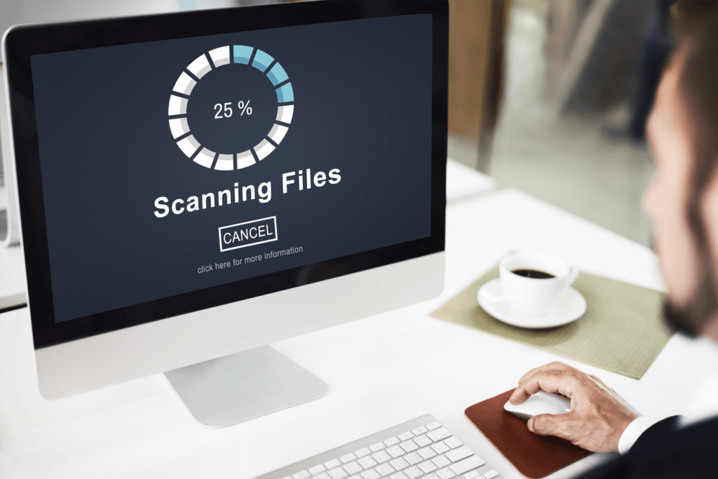 A man sits at a computer with a scan 25% of the way in progress to visualize a Chrome virus scan