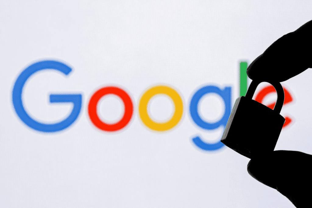 The silhouette of a person holding a padlock is seen with a blurry Google logo in the background, visualizing the company's Google Security Checkup feature.