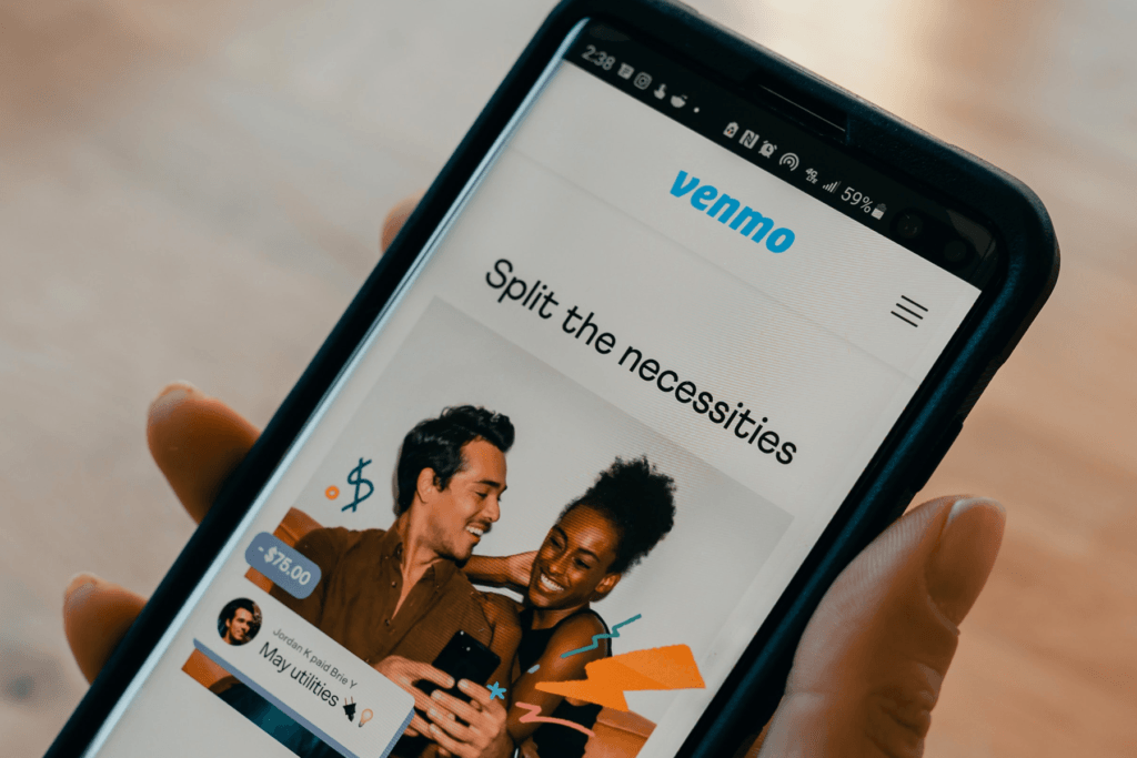 A person holds a phone open to the Venmo website app that encourages users to "Split the necessities" with friends. The designation is part of the answer for will Venmo refund money if scammed