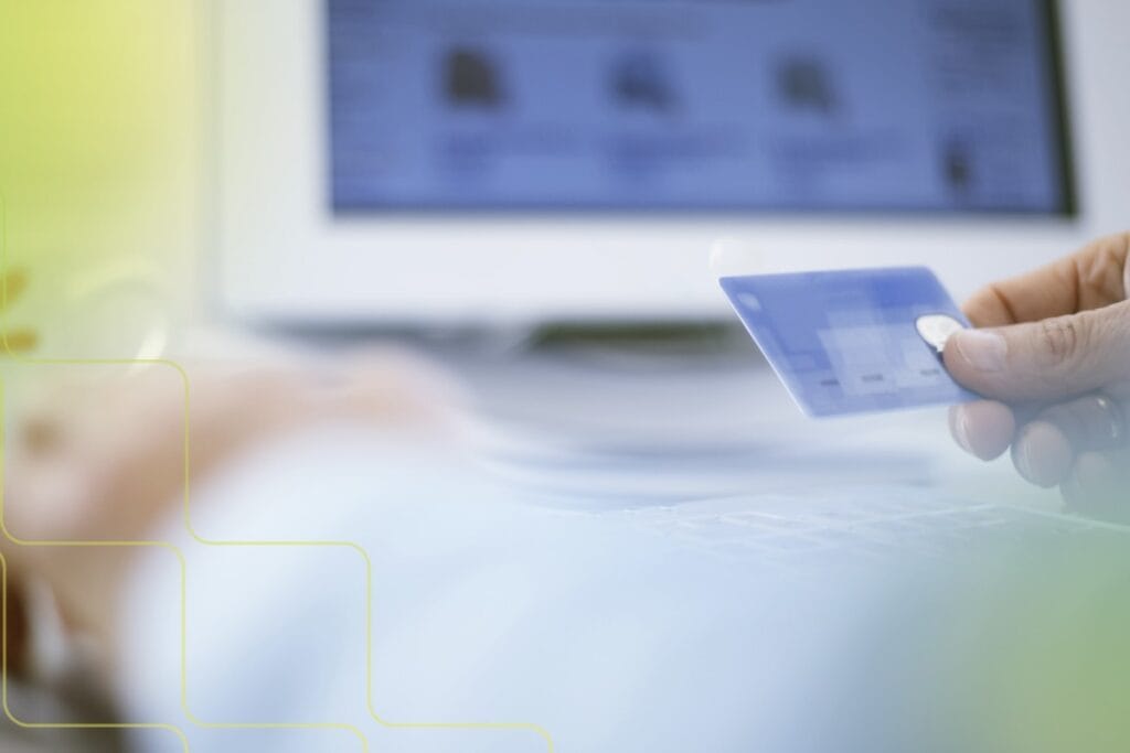person holding a credit card in front of a computer.