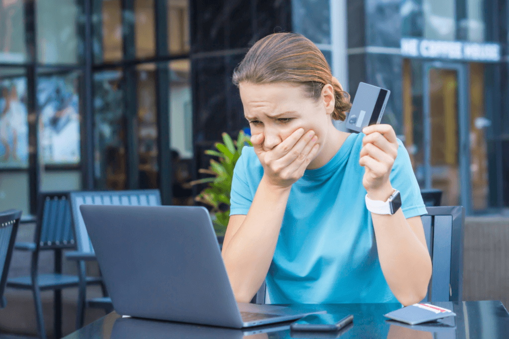 Photo of a woman in anguish holding a bank card in front of her device indicating that she did not follow basic online banking safety tips.