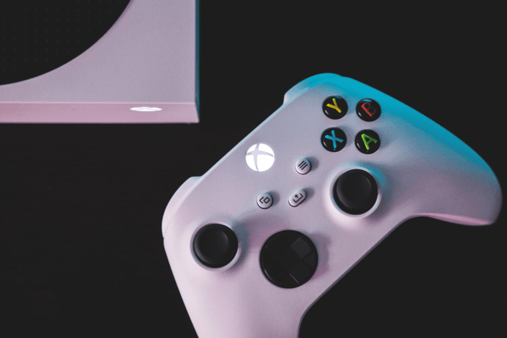 A white Xbox controller is seen on a black table, visualizing Xbox security tips.