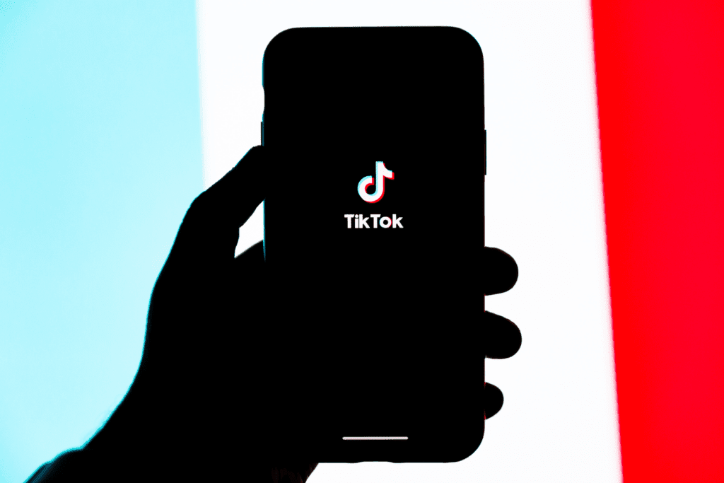 A person holds a cellphone that is opening the TikTok app. The TikTok app is a driving motivator to codify the RESTRICT Act into law