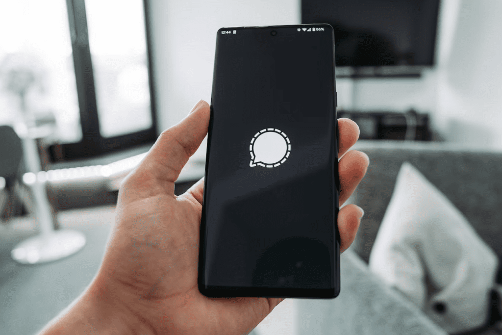 A person holds a smart phone that displays the Signal loading screen, visualizing how to delete Signal account data