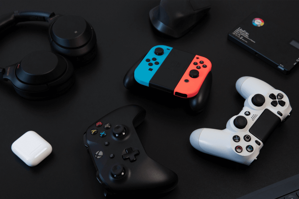 PlayStation, Nintendo, and Xbox game console controllers are seen on a dark table to visualize how to use VPN for gaming