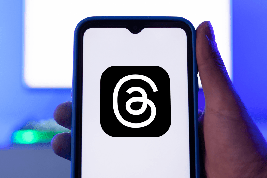 A person holds a smartphone open to the Threads app loading screen to visualize how to unblock Threads and use the new platform with a VPN