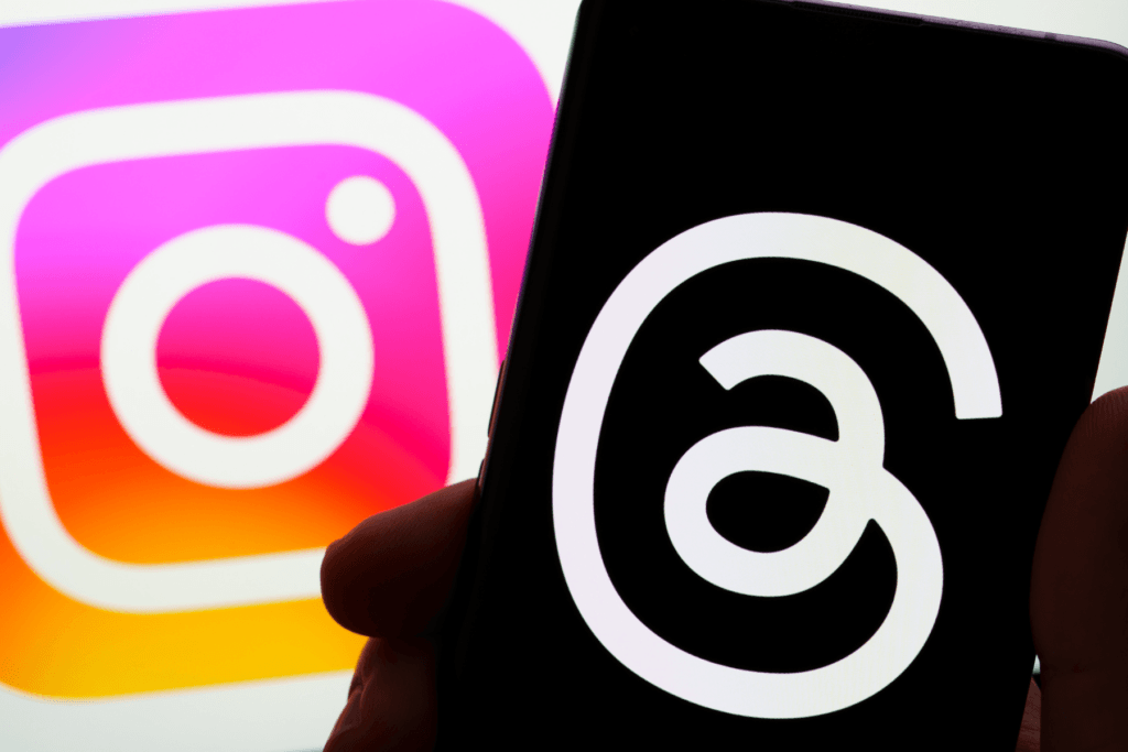 Photo of a person holding a phone showing what is Threads in front of the Instagram logo.