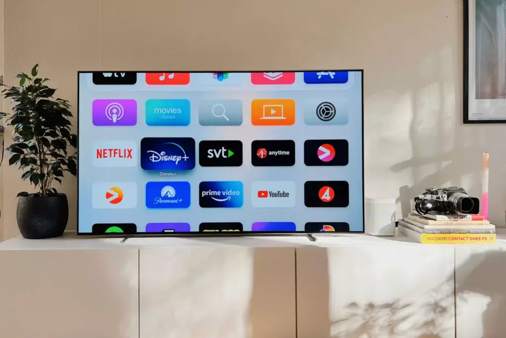 An TV sitting on an entertainment stand displays the Best Apple TV Apps available