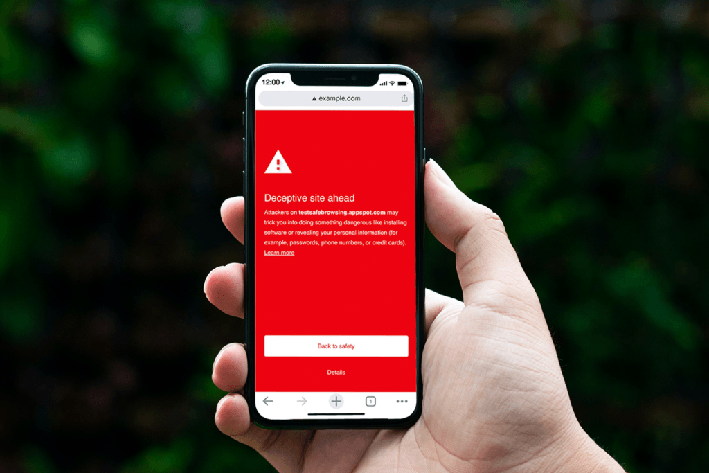 A person holds a phone in which the website they were going to was blocked by Google Chrome's Enhanced Safe Browsing because it was deemed malicious