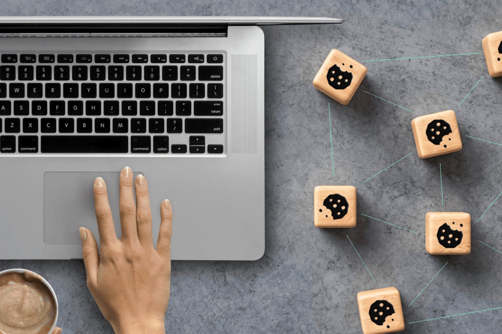 A person uses a laptop beside blocks of cookies that are interconnected to depict a cache vs cookies comparison