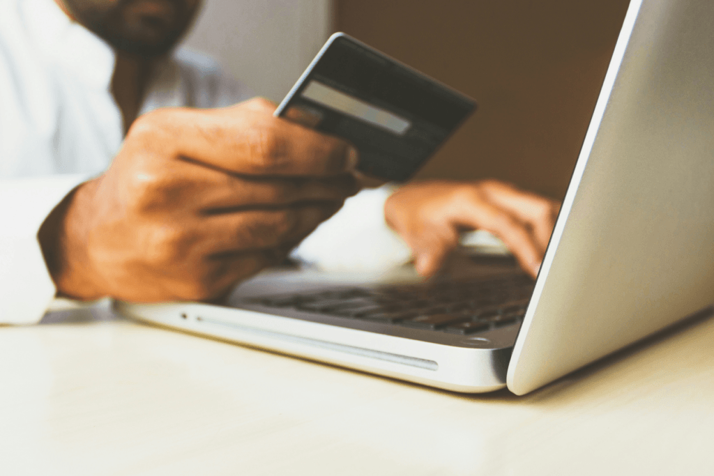A person holds a credit card to enter their details on a computer demonstrating how to buy a vpn
