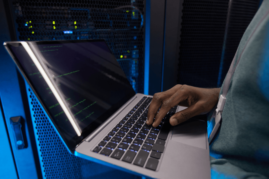 Decorative image for new server locations showing a person holding a laptop standing in front of a server rack