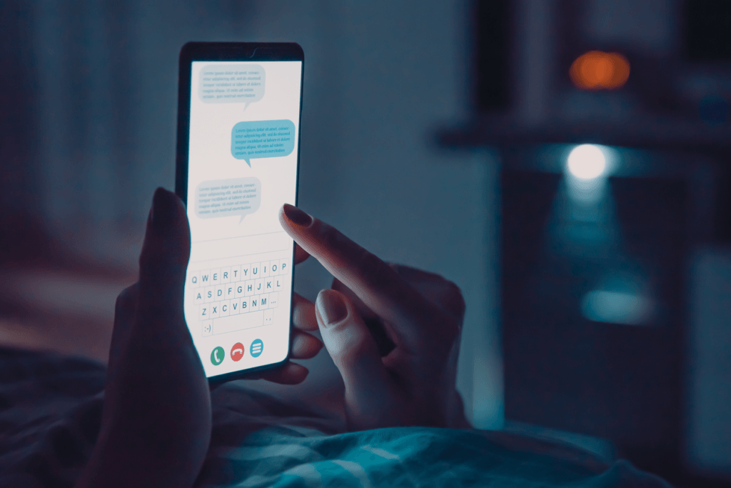 Decorative image for the benefits of reducing screen time shows a person using a mobile phone while laying in the dark