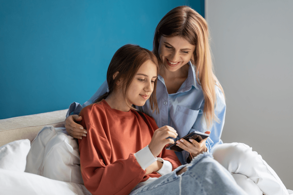 Decorative for article about Instagram Teen Accounts with a parent and teenager sit together looking at phone