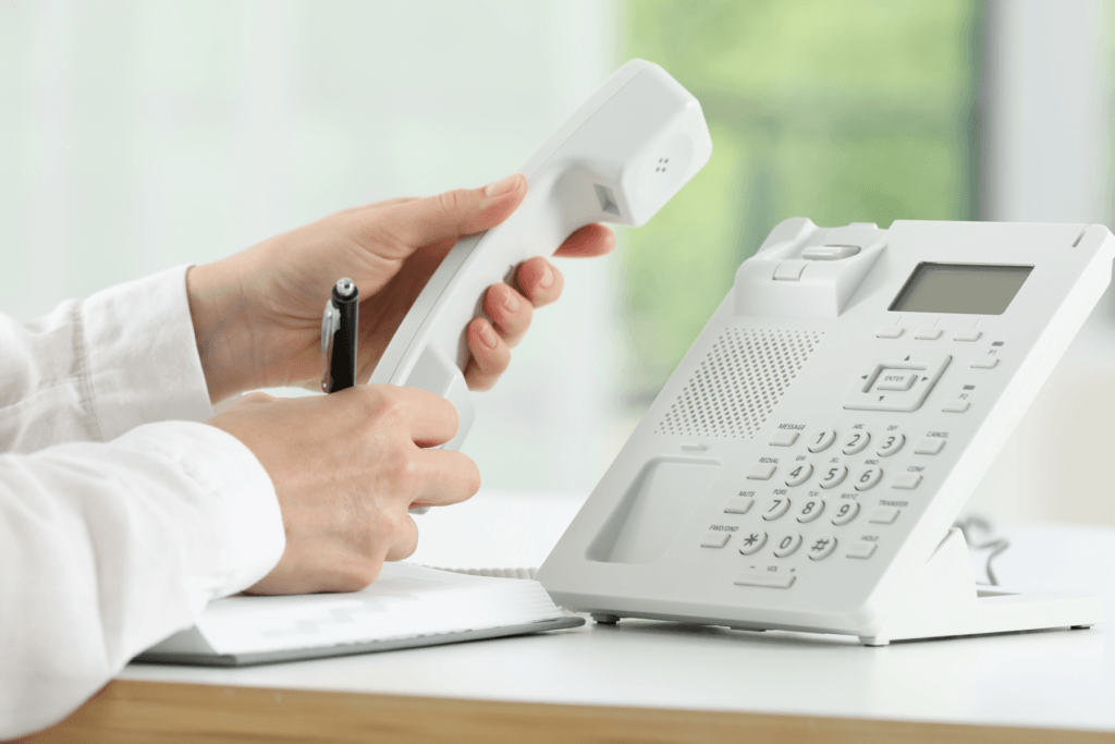 Decorative image for article about phone number privacy and what someone can do with your phone number. Image shows a person holding a landline office phone