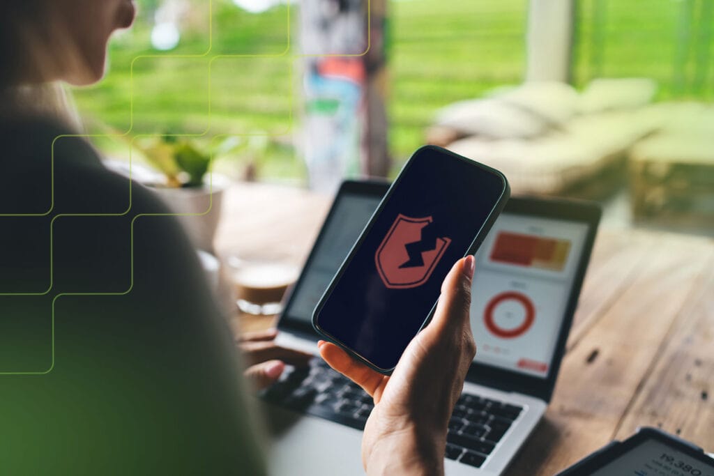 Person holding a phone displaying a broken shield icon meaning VPN vulnerabilities.